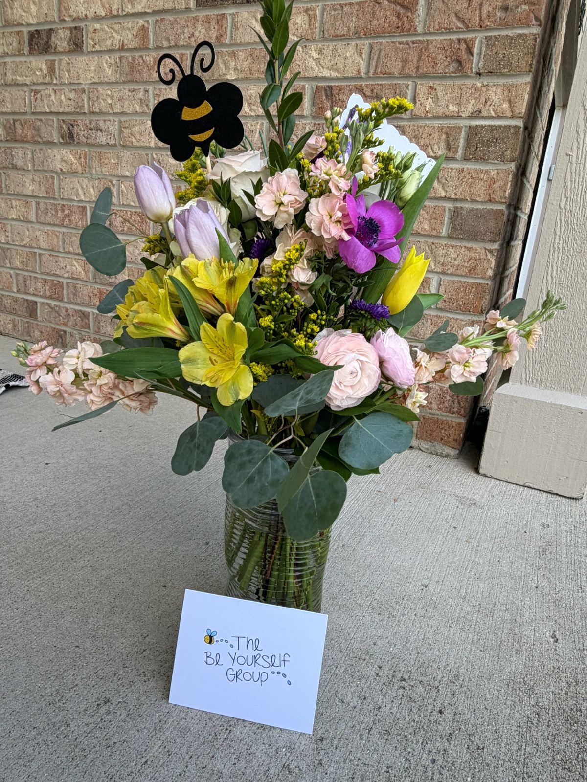 Spring arrangement with a bee accent and a Be Yourself Group card