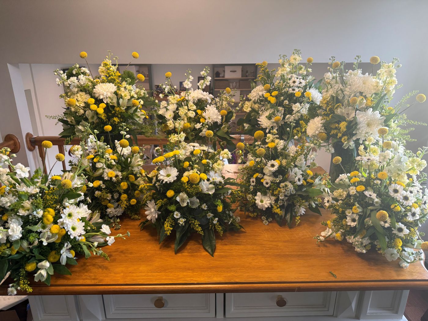 A spread of white and yellow arrangements ready for an event