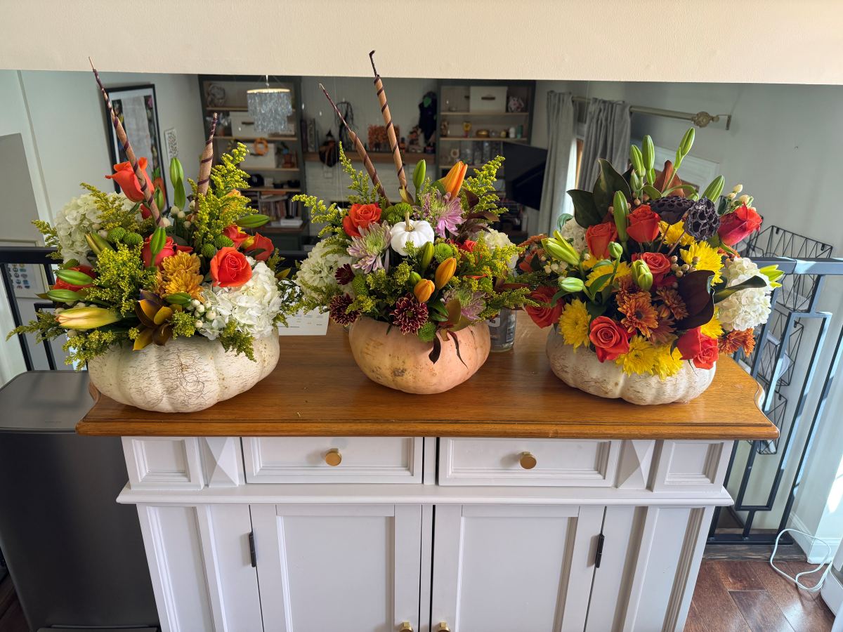 Three autumn arrangements in white pumpkin vases
